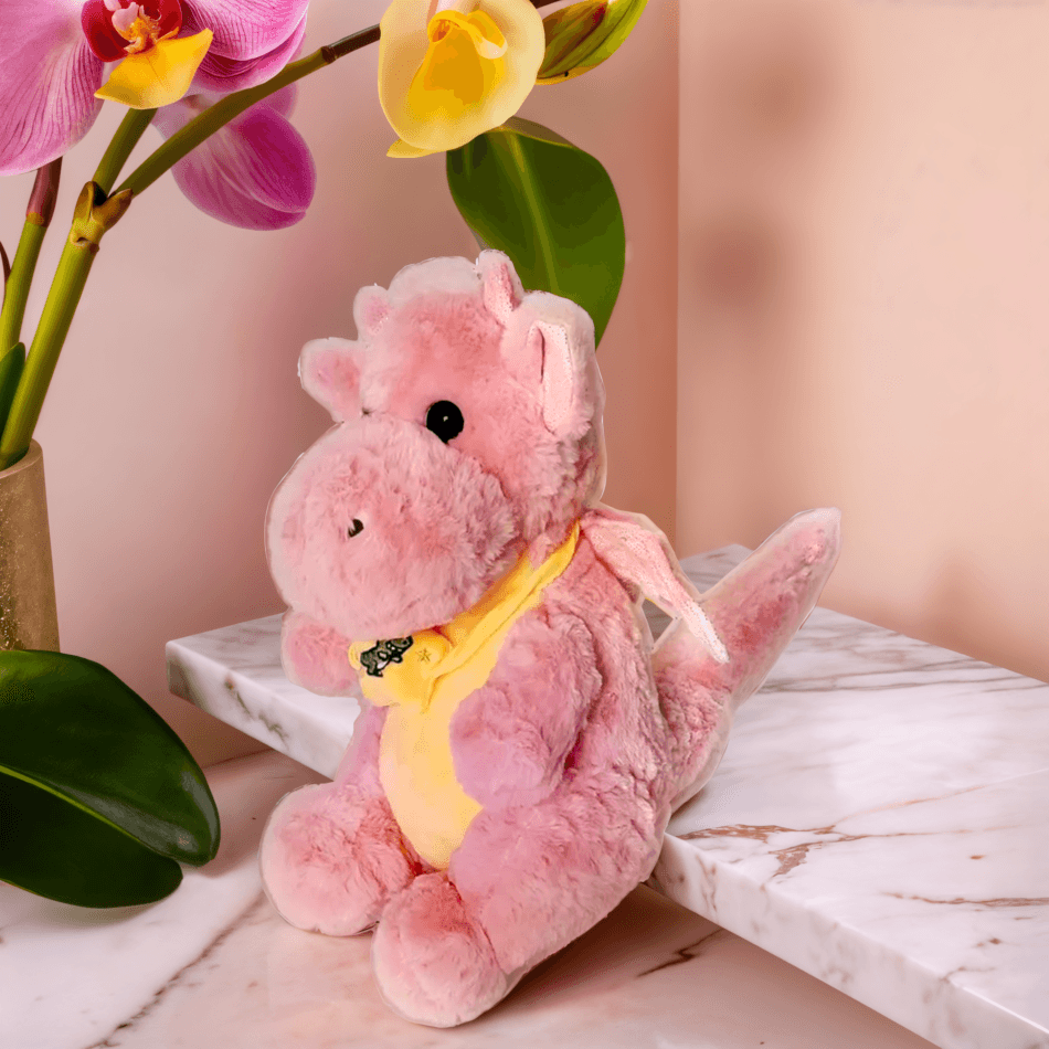 Close-up of Dinky the Dino, a soft pink dinosaur plush, showing its soft, safe fabric and adorable features